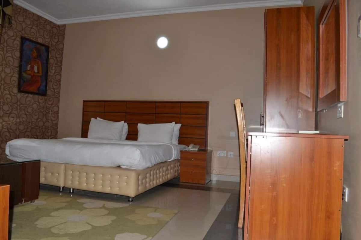 Un dormitorio con una cama grande, cabecera de madera y un armario de madera.