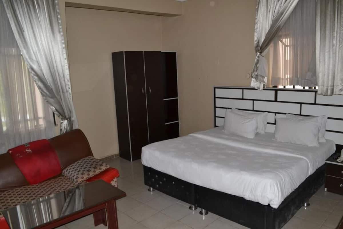 Un dormitorio con cama, armario, sofá y mesa.