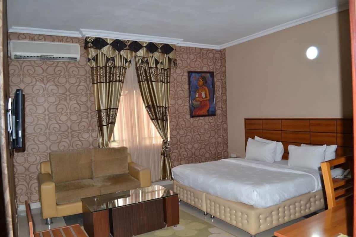 Una habitación de hotel con una cama, un sofá, un televisor y un cuadro en la pared.