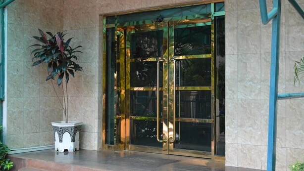 L'ingresso di un edificio con una porta in vetro, una pianta in vaso e un pavimento piastrellato.