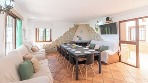 A spacious living area with a dining table, sofas, and a stone wall. - Finca Salrima Álora by Ruralidays (Málaga)