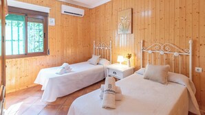 A room with two beds, a window, an air conditioner, and a painting on the wall. - Finca Salrima Álora by Ruralidays (Málaga)
