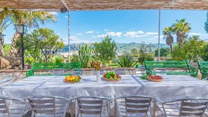 An outdoor dining area with a table set for four, surrounded by green chairs and a white tablecloth. - Finca Salrima Álora by Ruralidays (Málaga)