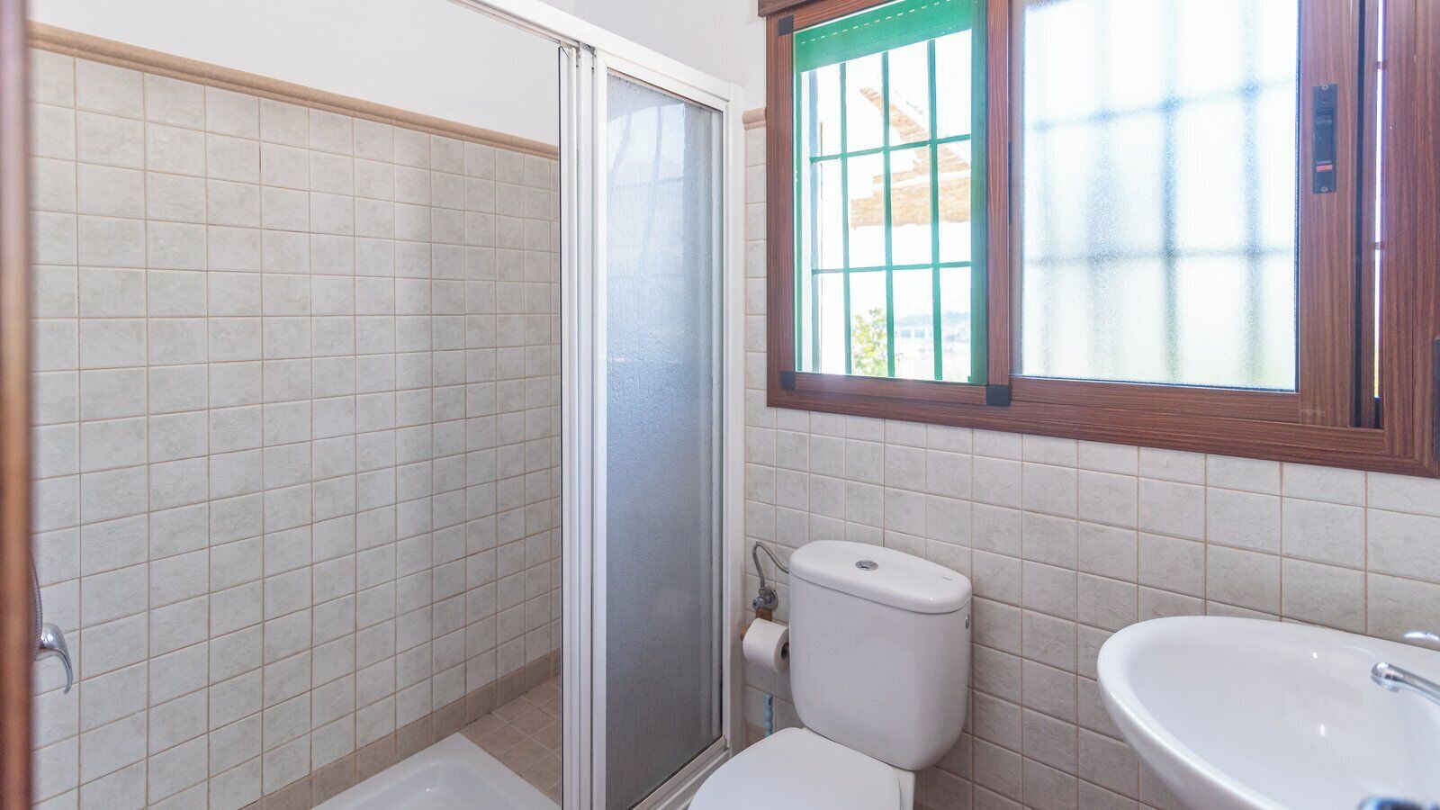 Et badeværelse med bruser, toilet og håndvask.