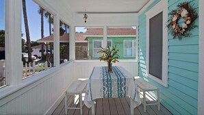 Een overdekt terras met een tafel en stoelen, een decoratieve krans, en uitzicht op een groen gebouw met 'Integria' aanduiding.