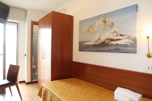 Habitación de hotel con cama, un cuadro de querubines en la pared, una silla y un armario de madera.
