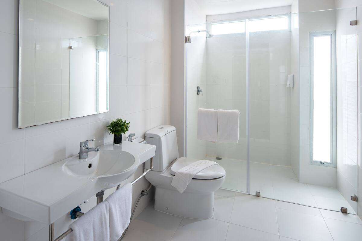 Une salle de bain moderne avec un lavabo blanc, des toilettes et une douche à parois de verre.