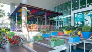 A covered outdoor seating area with colorful planters and a bicycle. - Eco Inn Prime Mae Sot (Mae Sot)