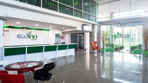 A modern reception area with a green and white color scheme, a reception desk, and a glass door leading to the outside. - Eco Inn Prime Mae Sot (Mae Sot)