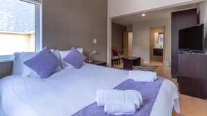 A hotel room with a large bed, a TV, and a desk. - Cisco Moon (Kutchan)