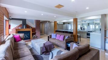 Una sala moderna con chimenea, sofás y una cocina al fondo.