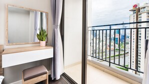 Een modern appartement met balkon, grote spiegel, een potplant en uitzicht op een stadsgezicht.