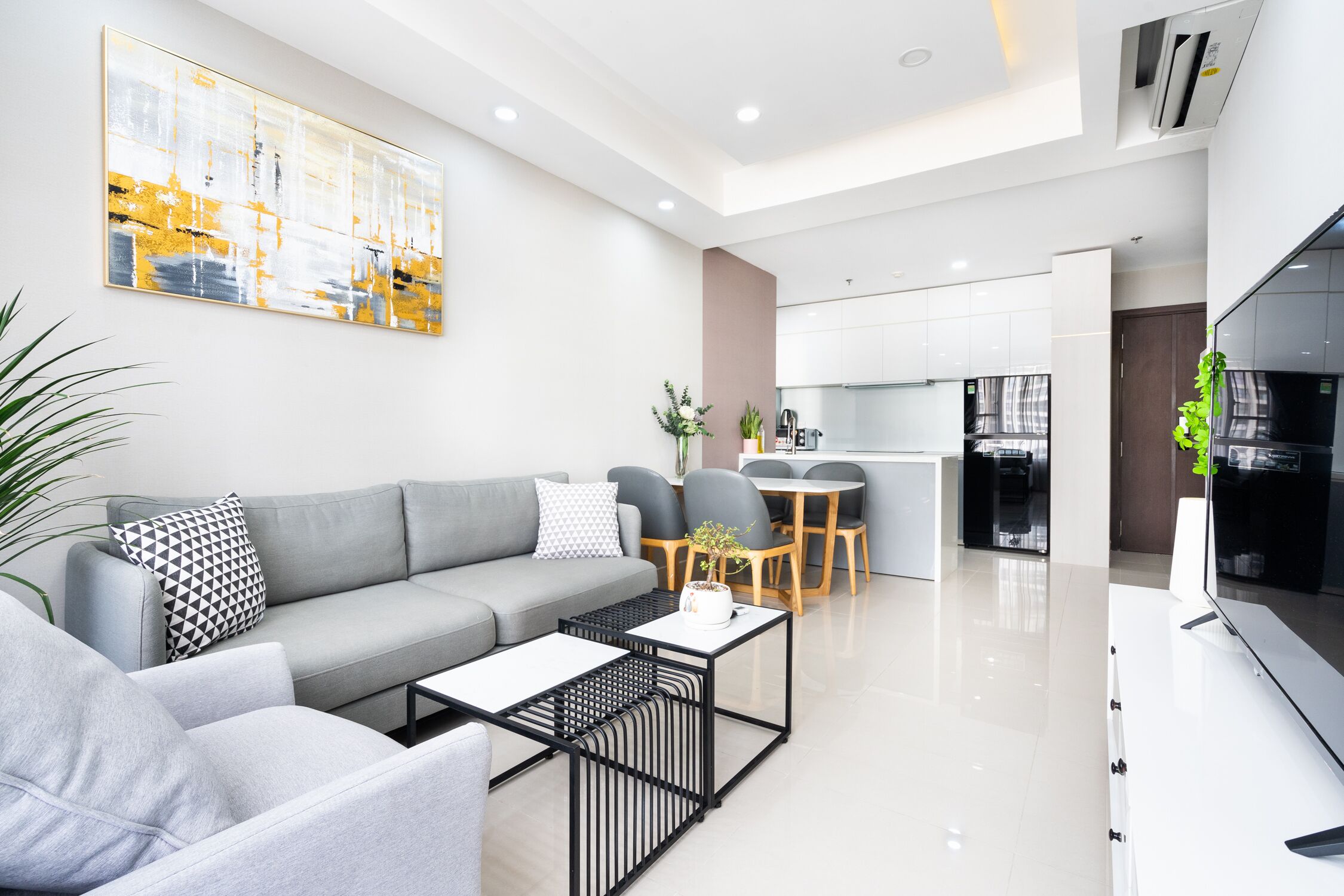 A modern living room with a grey sofa, a coffee table, and a dining area with a table and chairs.