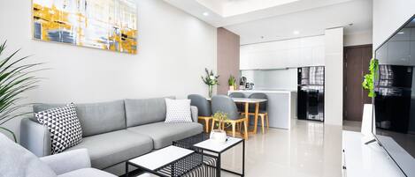 A modern living room with a grey sofa, a coffee table, and a dining area with a table and chairs.