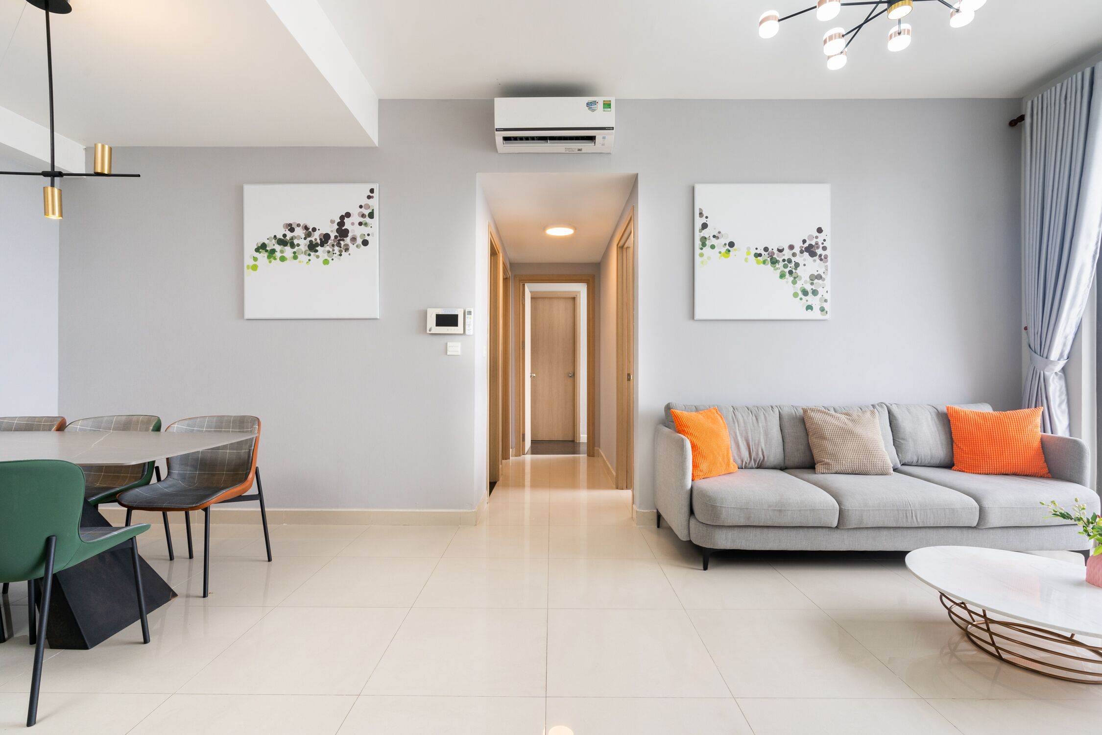 Una sala de estar moderna con un sofá gris, una mesa de comedor con sillas y obras de arte en las paredes.