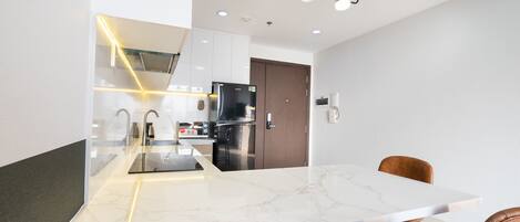 A modern kitchen with a marble countertop, stainless steel appliances, and a dining area with leather chairs.