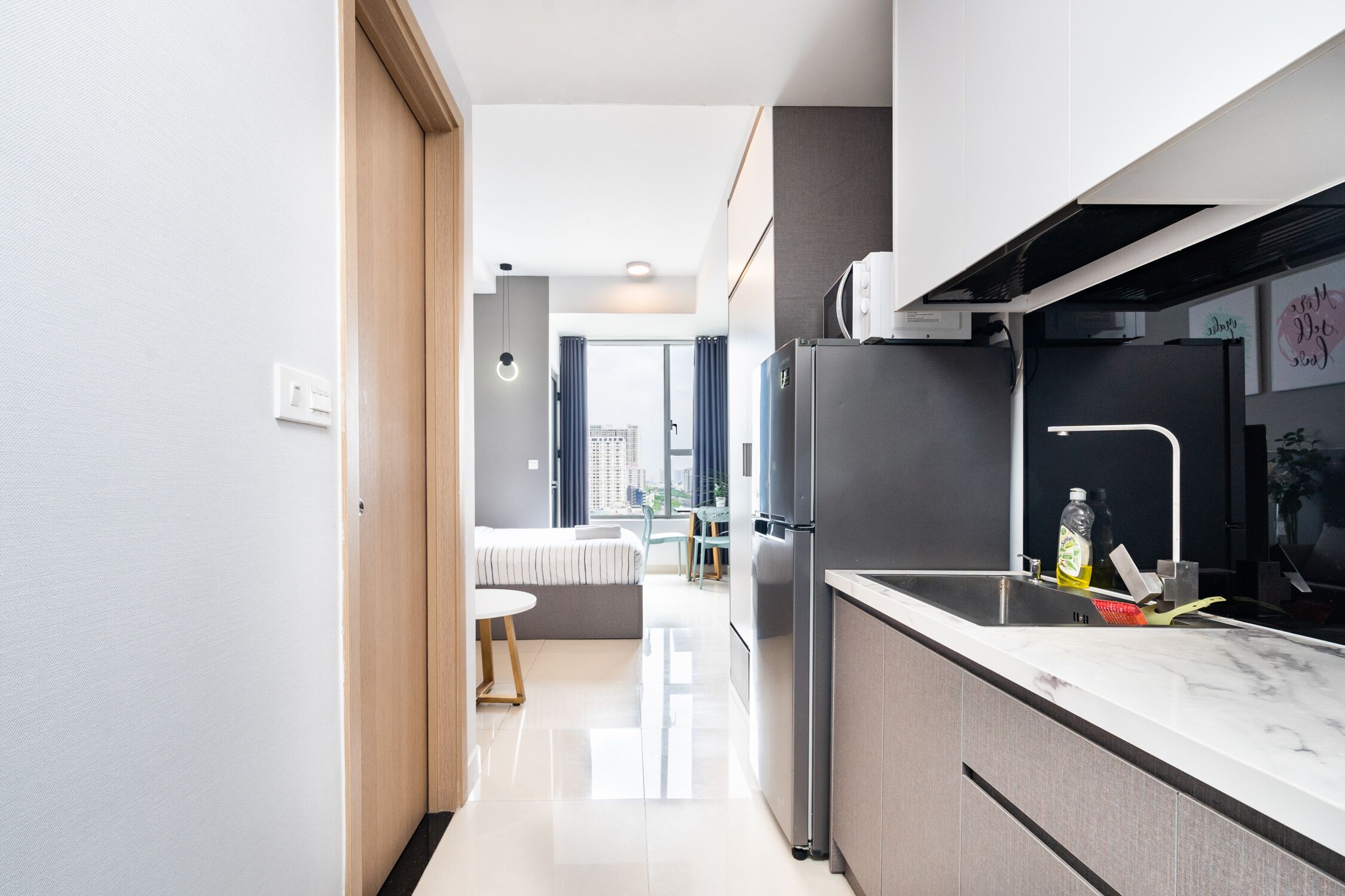 Una cocina moderna con un refrigerador de acero inoxidable, un lavamanos y una encimera de mármol.
