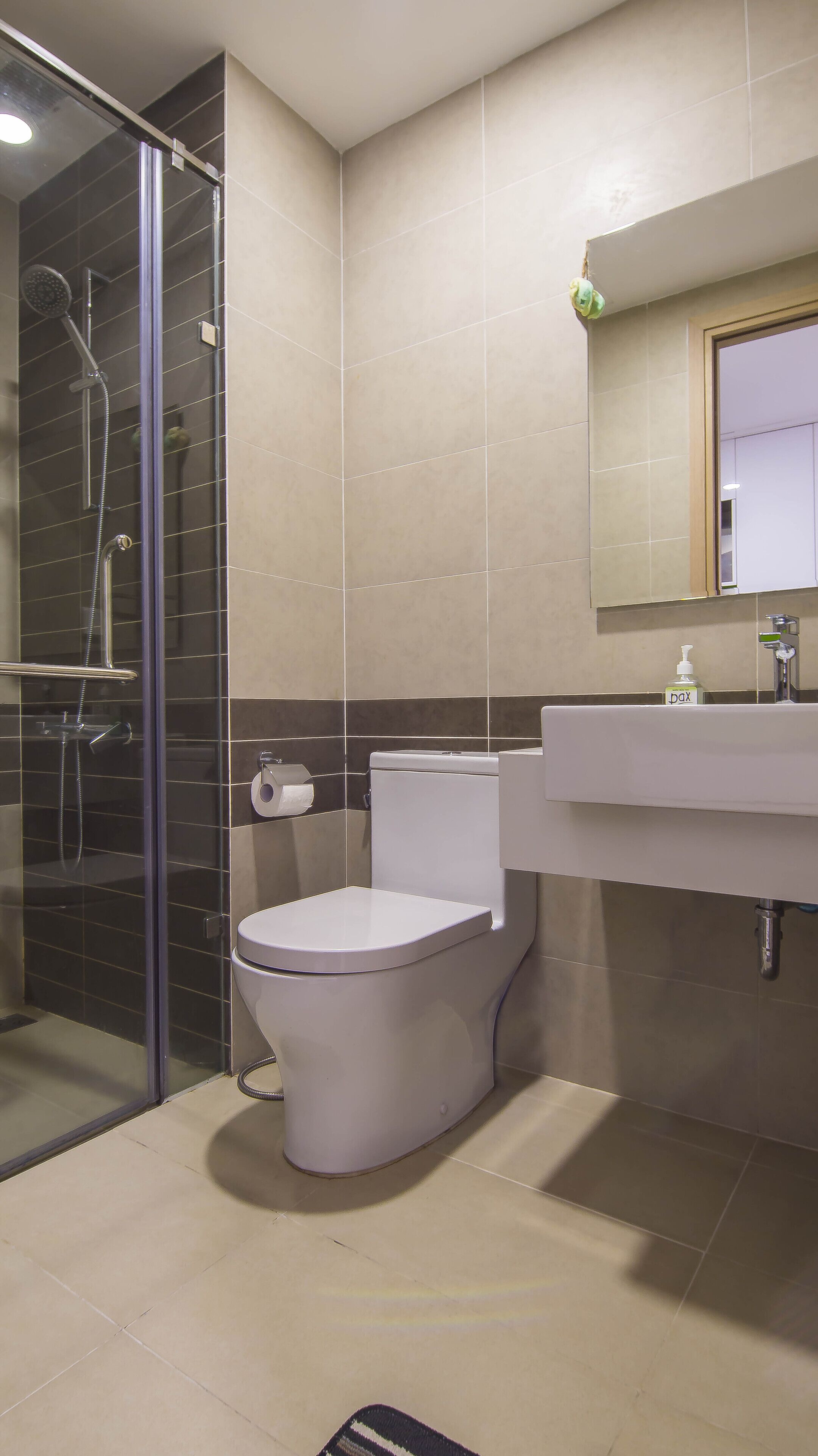 A modern bathroom with a glass shower enclosure, a toilet, and a sink with a mirror above.