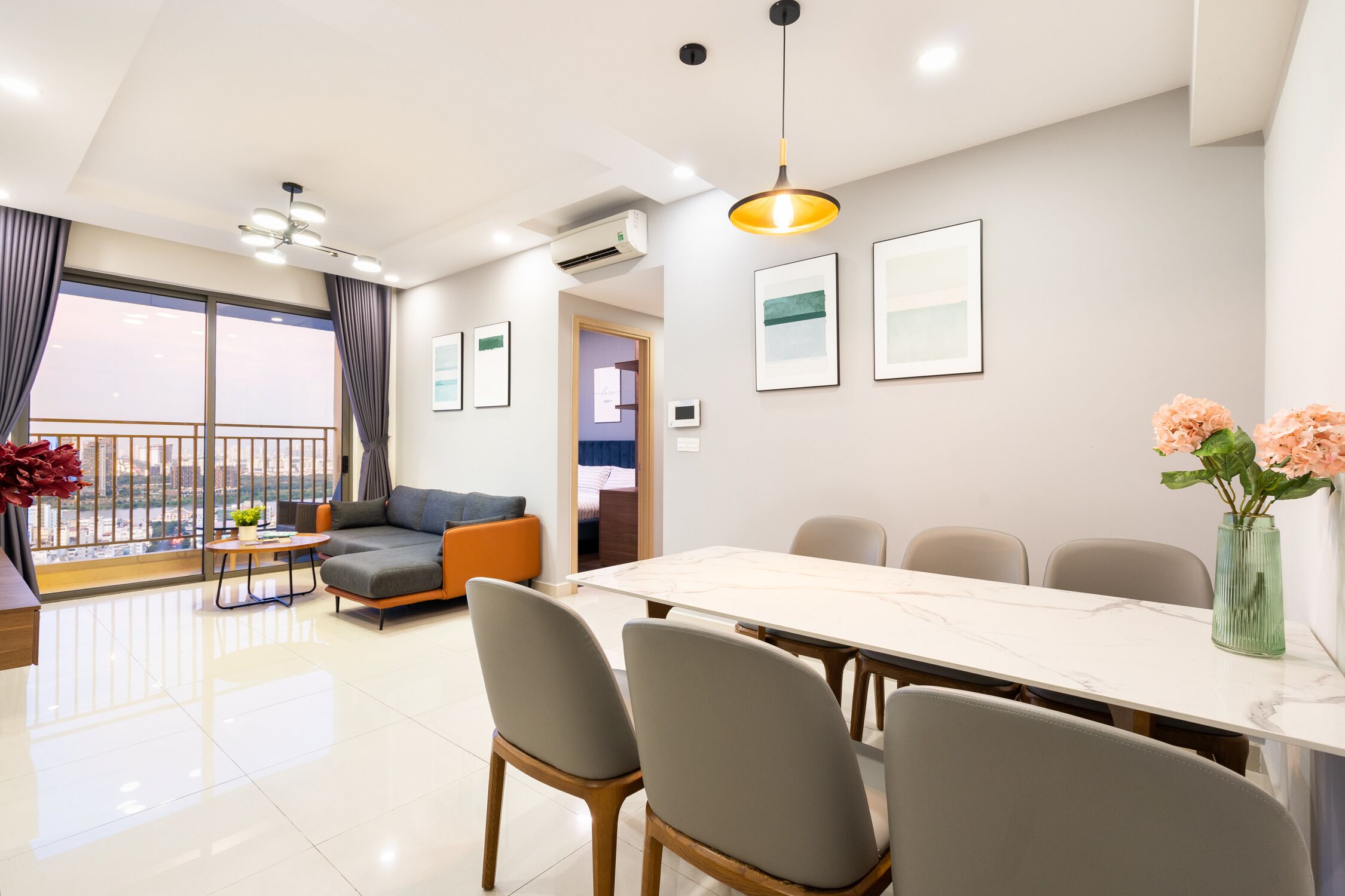 A modern living room with a dining area, large windows, and a balcony.
