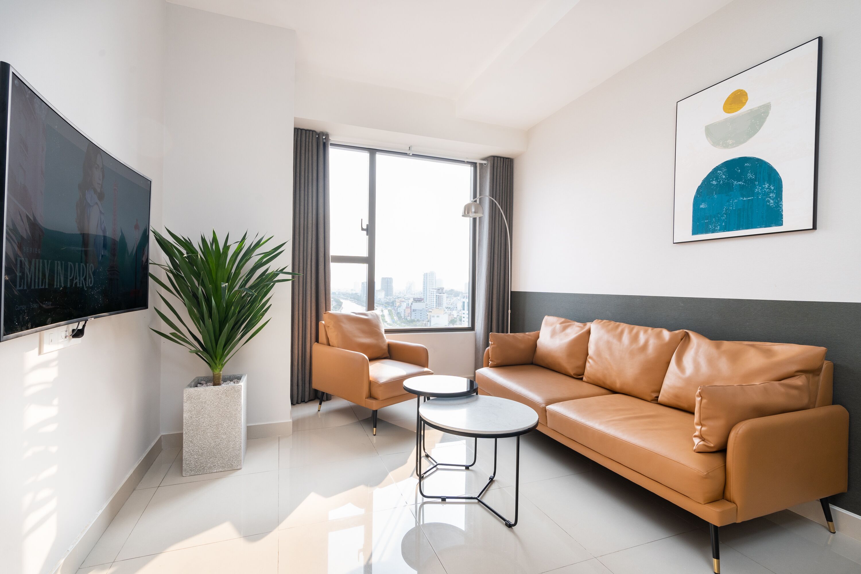 A modern living room with a sofa, a coffee table, a TV, and a large window with curtains.