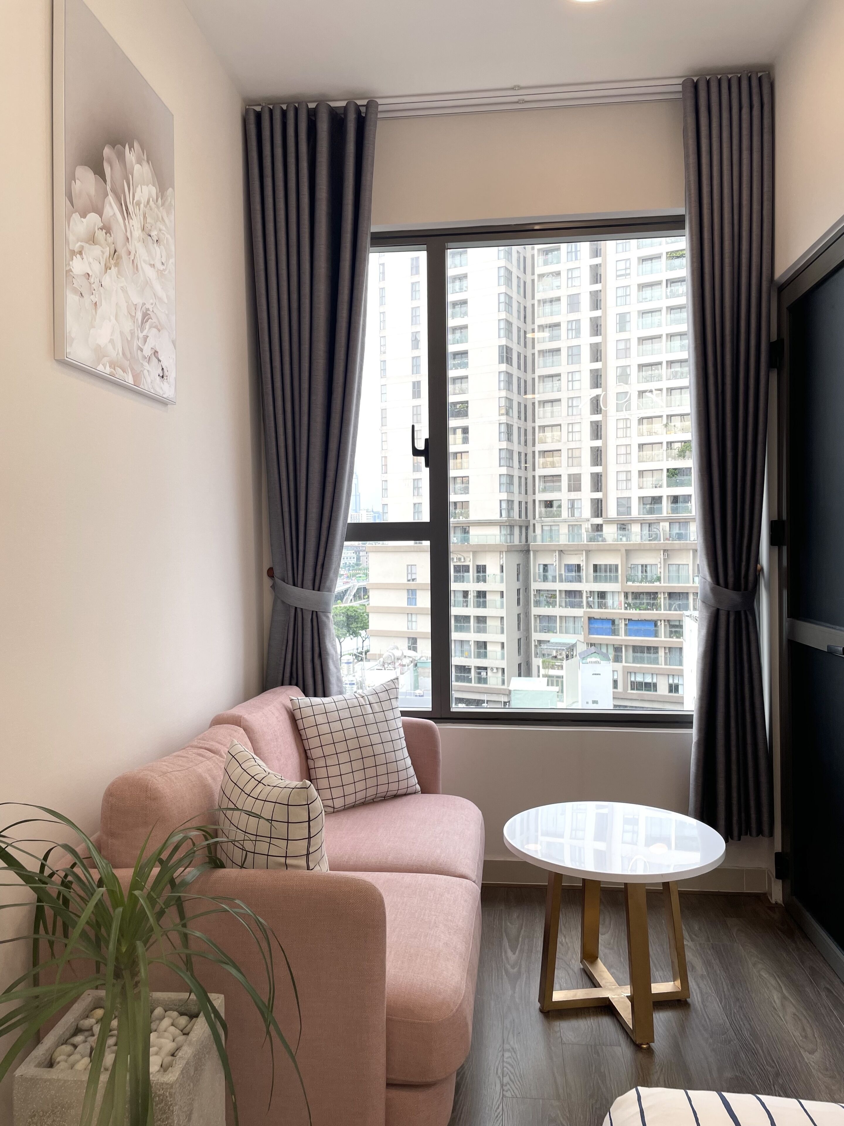 A modern living room with a pink sofa, a round coffee table, and a large window with curtains.