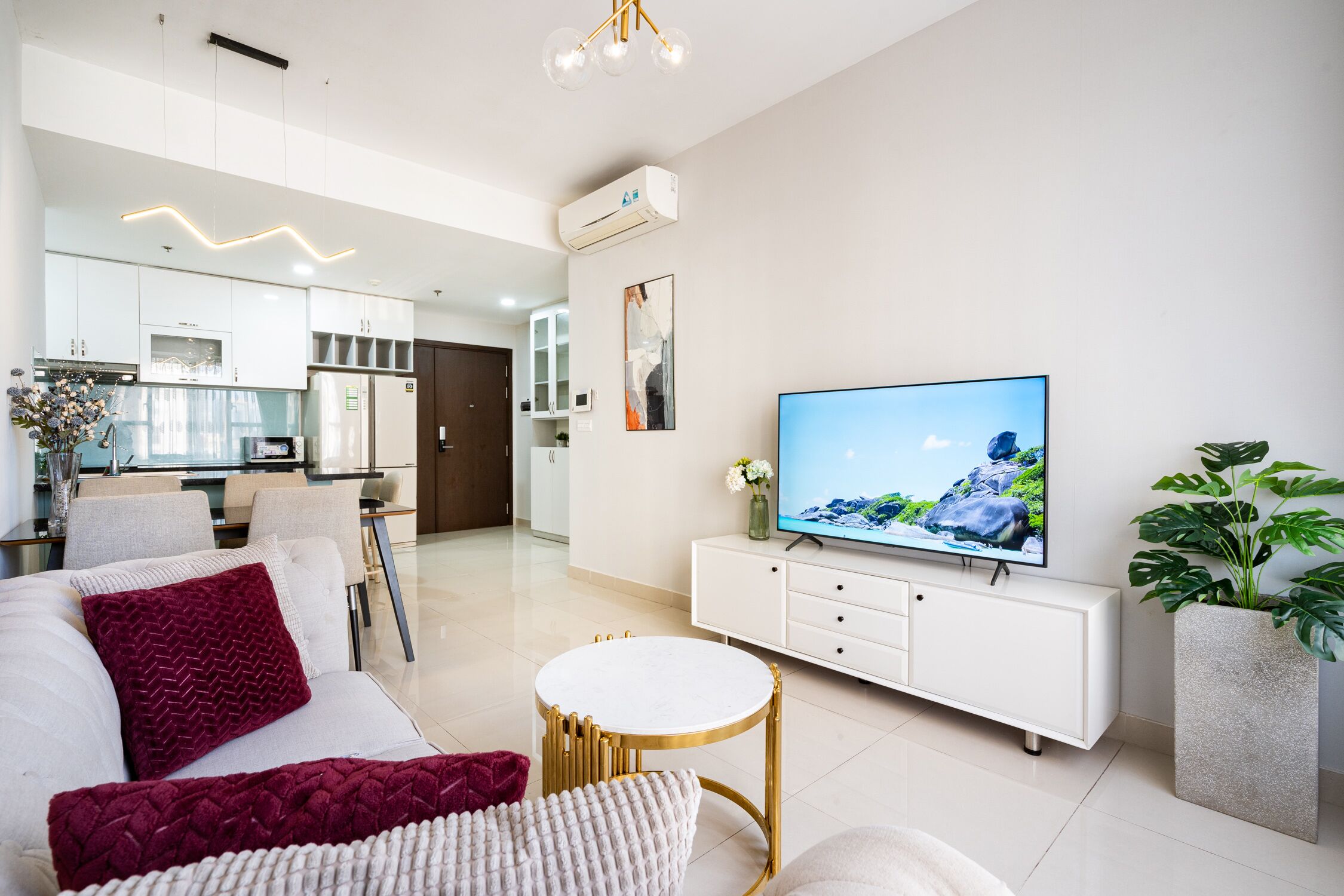 A modern living room with a white sofa, a round coffee table, a flat-screen TV, and a white cabinet.