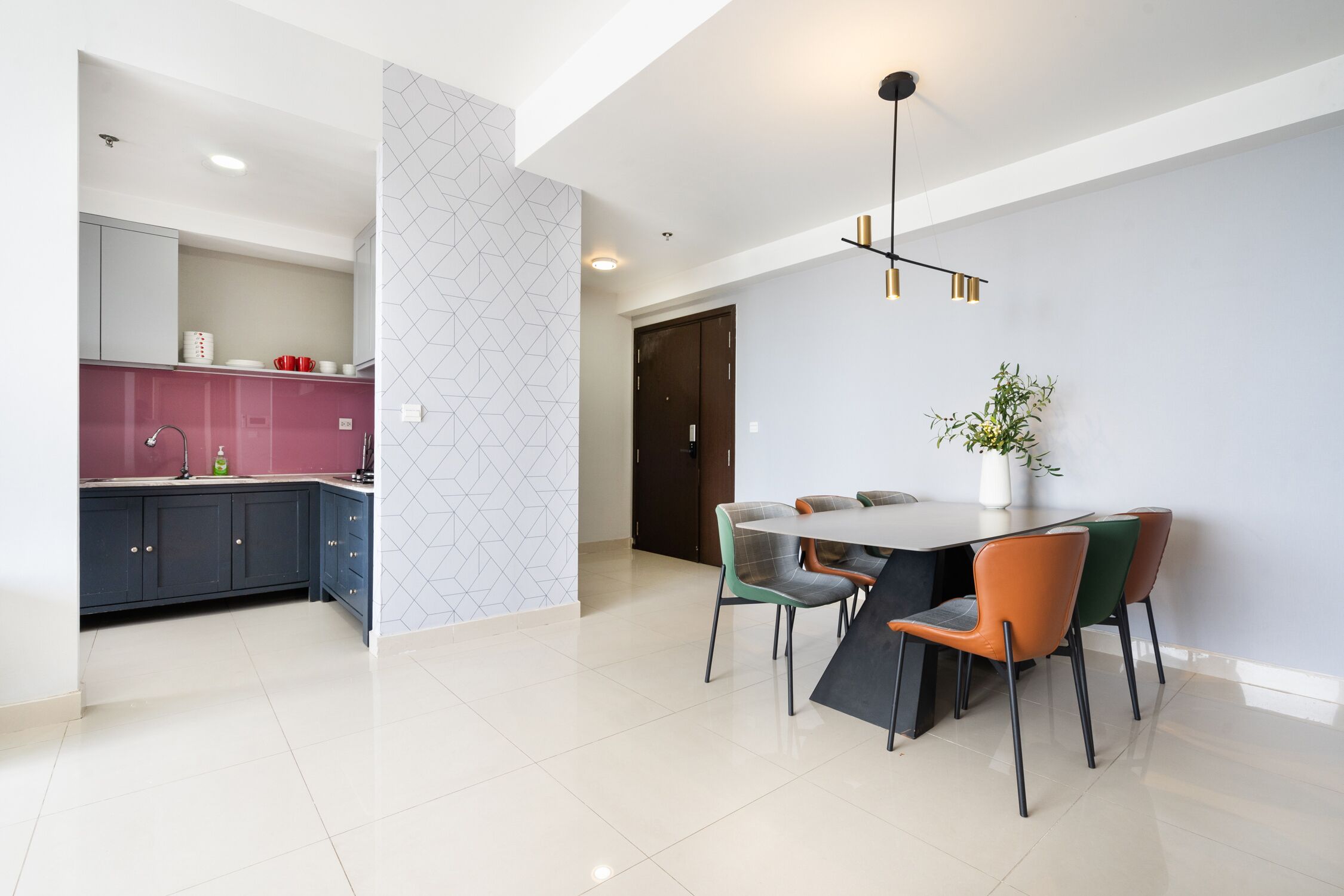 A modern kitchen with dark cabinets, a pink backsplash, and a dining area with a table and chairs.