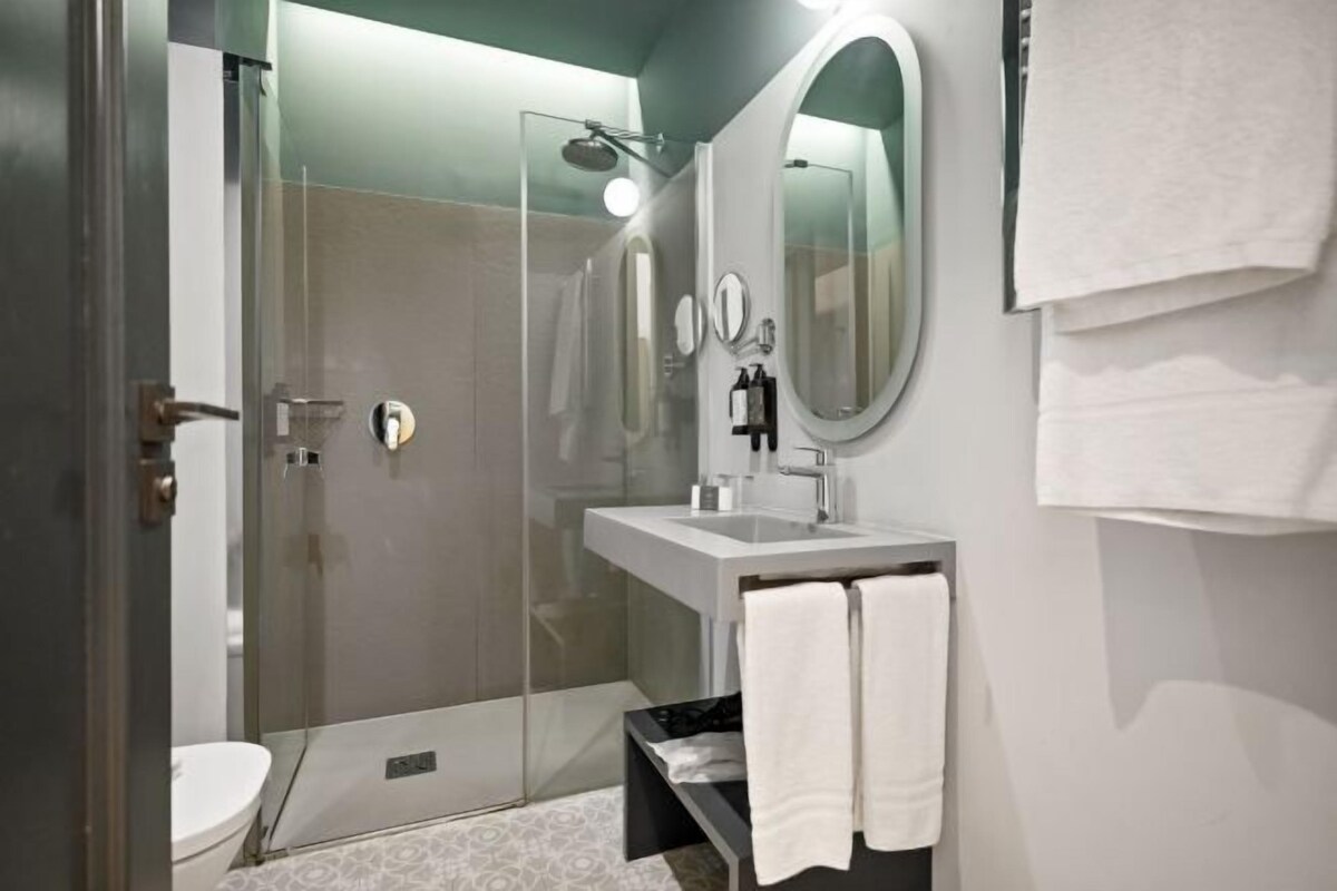 A modern bathroom with a glass-enclosed shower, a white sink, and a large mirror.