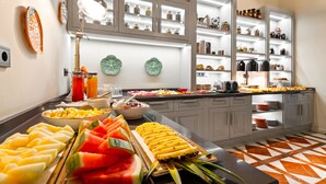 A buffet area with various food items and a well-organized kitchen in the background. - Joya del Casco Boutique Hotel (Seville)