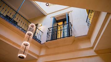 Un intérieur à plusieurs niveaux, doté d’un plafond en verre, d’un escalier et d’un balcon avec une balustrade.