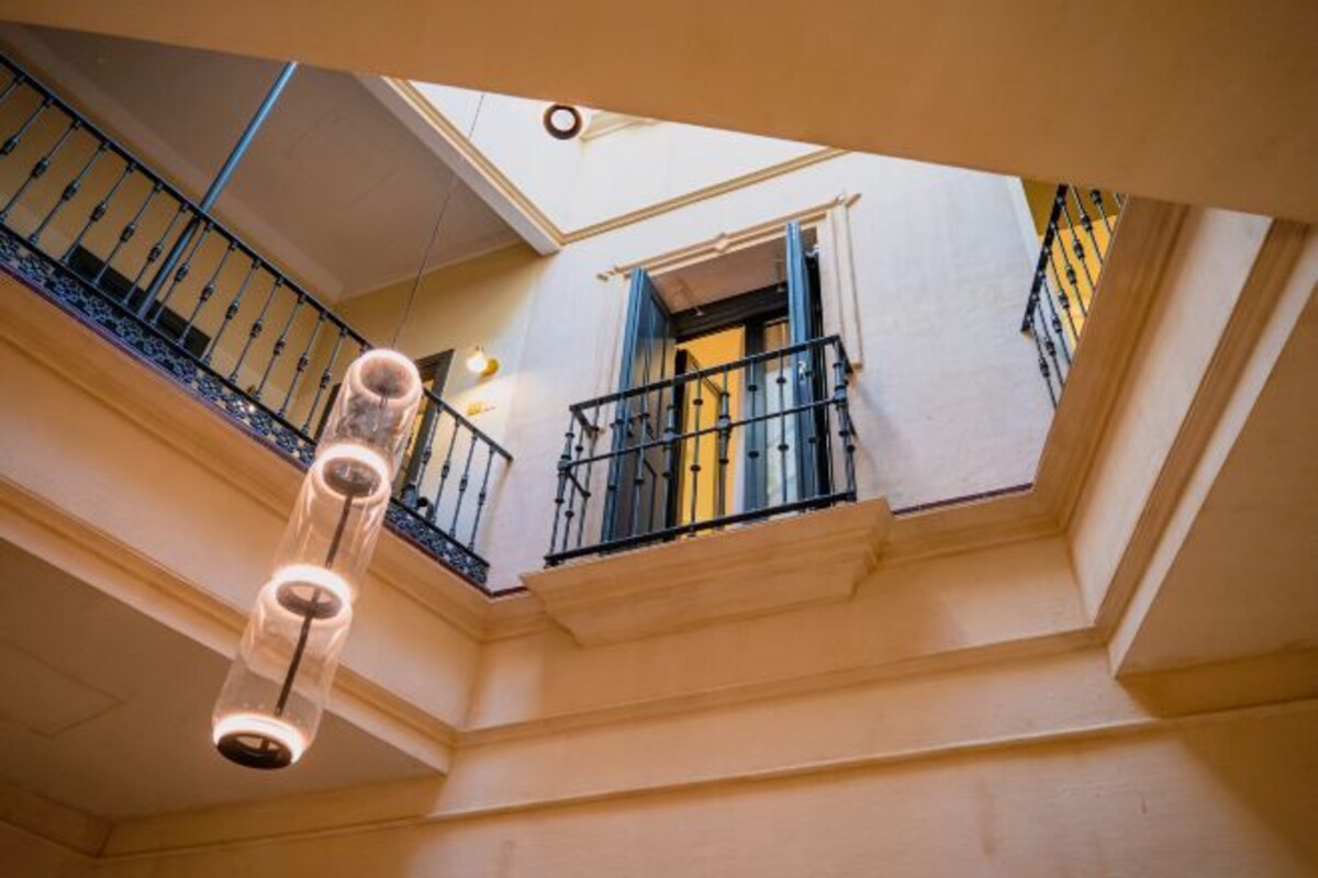 A multi-level interior with a staircase, a hanging light fixture, and a window with blue shutters.