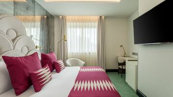 Quarto de hotel com cama grande, uma escrivaninha, uma cadeira e televisão.
