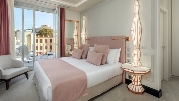 A hotel room with a large bed, a sitting area, and a view of the city through large windows. - Room Mate Gran Filippo I, Roma-Fontana di Trevi (Rome)