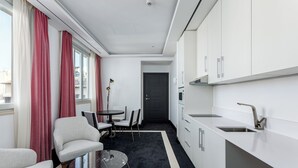 A compact hotel room with a kitchenette, a dining area with a table and chairs, and a seating area with a sofa and armchair. - Room Mate Gran Filippo I, Roma-Fontana di Trevi (Rome)