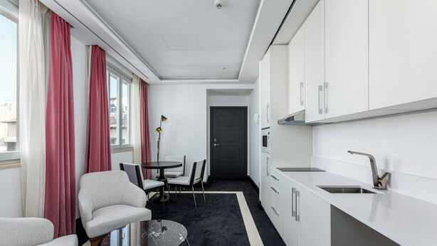 A compact hotel room with a kitchenette, a dining area with a table and chairs, and a seating area with a sofa and armchair. - Room Mate Gran Filippo I, Roma-Fontana di Trevi (Rome)