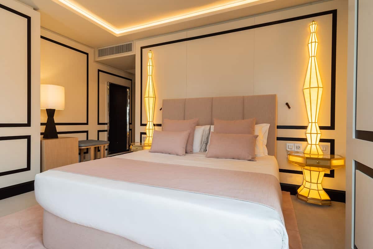 Habitación de hotel con una cama grande, mesitas de noche, una lámpara y un aplique de pared.