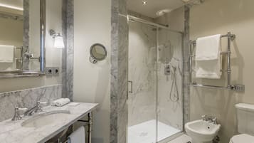 A modern bathroom with a marble vanity, a glass-enclosed shower, and a toilet.
