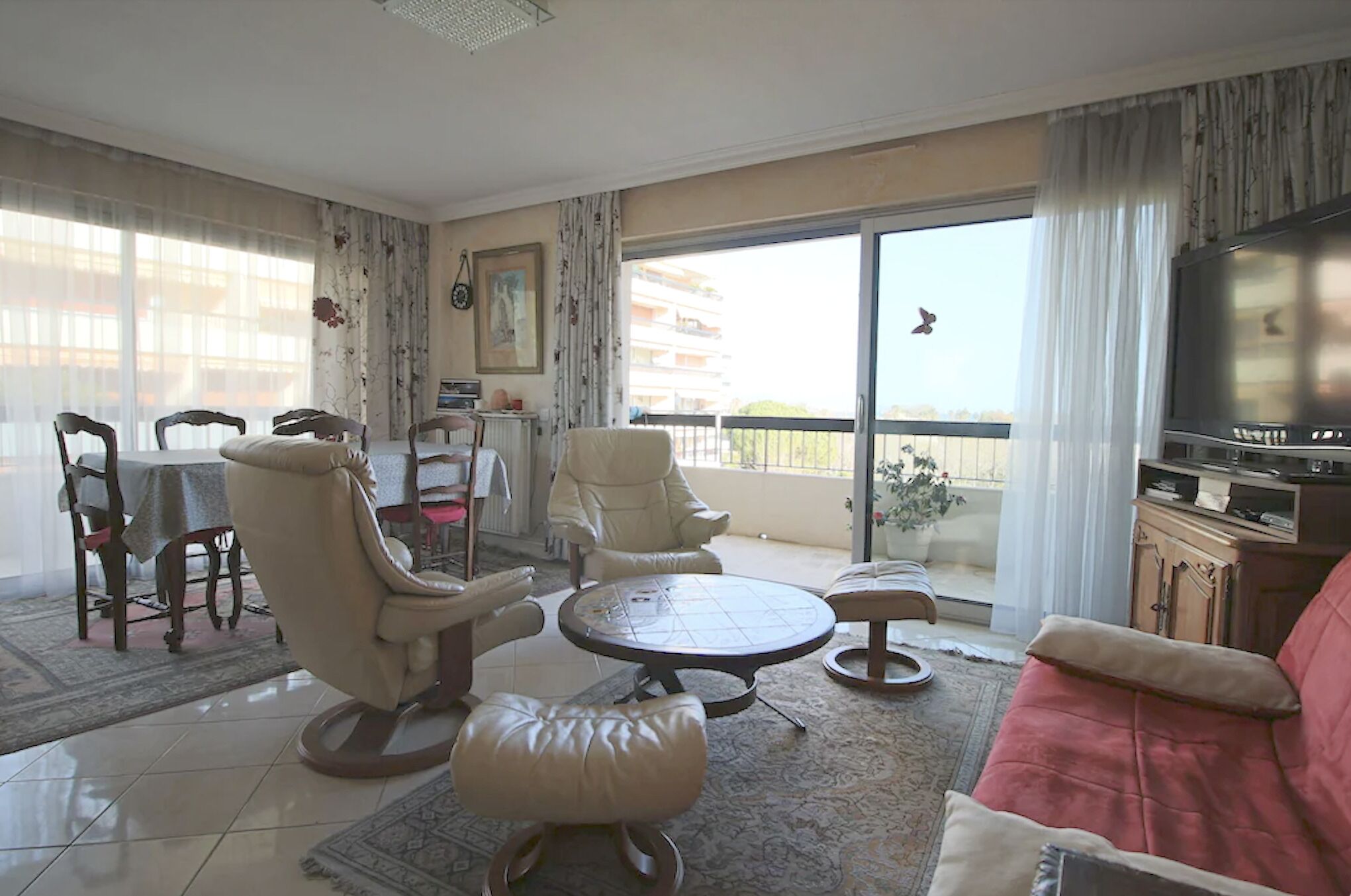 A living room with a sofa, chairs, a dining table, and a TV.