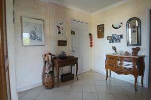 A room with a wooden desk, a dresser, and a door. There are framed pictures on the walls and a mirror above the dresser.