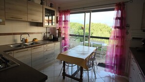 A modern kitchen with a dining area, large windows, and a view of greenery. - VILLENEUVE LOUBET BEACH 5MN FROM BEACHES, 2 BEDROOMS 2 BATHROOMS SEA VIEW, TENNIS  (Villeneuve-Loubet)