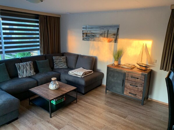 A modern living room with a sectional sofa, a coffee table, a cabinet, and a painting on the wall. - RBR 655 - Beach Resort Kamperland (Kamperland)