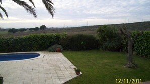 Un patio trasero con piscina, césped y vista a un paisaje lejano.