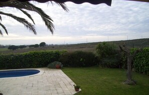 Un patio trasero con piscina, césped y vista a un paisaje lejano.