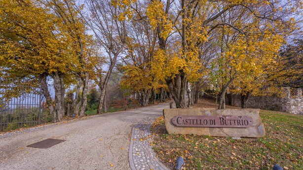 A paved pathway leading to a stone sign with the inscription "Castello Di Buttrio." - Buttrio Appartamento nel Verde (Buttrio)