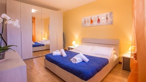 A hotel room with a large bed, a bedside table with a lamp, a mirror, and a painting on the wall. - Buttrio Appartamento nel Verde (Buttrio)