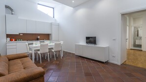 A compact living space with a kitchenette, dining area, and a TV on a white cabinet. - Ricasoli Garden Modern Apartment (Udine)