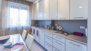 A modern kitchen with white cabinets, a stainless steel sink, and a wooden countertop.