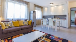 A modern living room with a sofa, coffee table, and a dining area with chairs and a table.