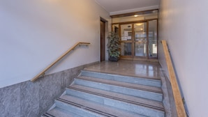A staircase with marble steps and wooden handrails leading to a glass door entrance.
