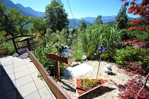 A garden with a wooden bench, a sign, and a small pond. - ★ Sunny apartment / WiFi / parking / pool / 5 people ★ (Bad Goisern am Hallstättersee)